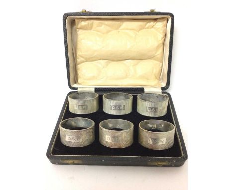 Set of six silver napkin rings with engine turned decoration and engraved initials, and family crest, in fitted box. Elkingto