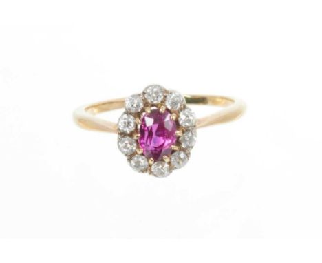 Ruby and diamond cluster ring with an oval mixed cut ruby measuring approximately 6mm x 4.5mm surrounded by ten old cut diamo