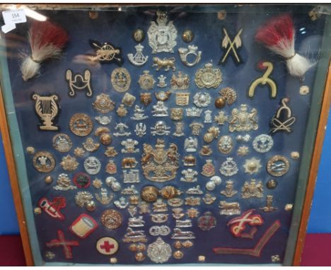 Framed and mounted display case of Victorian and later military cap badges and insignia including fusilier hackles, Victorian