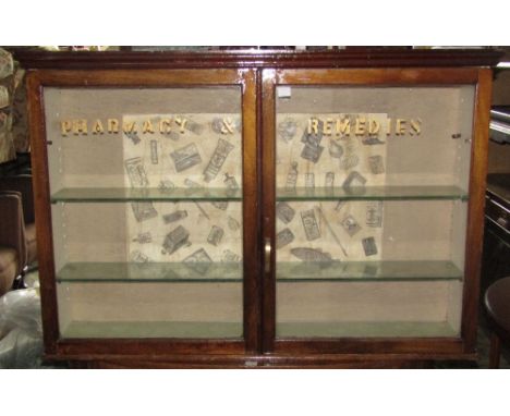 A vintage mahogany wall mounted display cabinet enclosed by a pair of rectangular glazed panelled doors with painted letterin