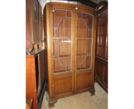 A 1920/30 oak veneered side cabinet, free standing and enclosed by a pair of partially glazed and leaded light panelled doors