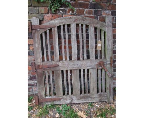 A weathered soft wood pedestrian gate with open vertical slats beneath an arched rail, 100 cm wide approx