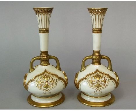 A pair of late 19th century Royal Worcester ivory ground two handled vases with moulded and pierced gilt decoration and green