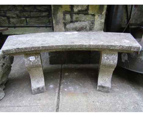 A weathered contemporary cast composition stone three seat garden bench with curved slab seat and shaped supports