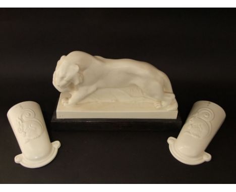 An Art Deco white glazed model of a lioness with prey raised on a rectangular wooden base, 37 cm max length, together with a 