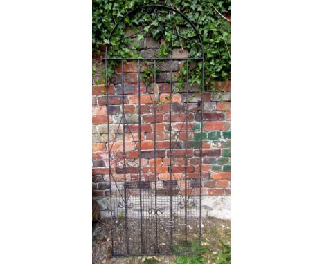 An iron work pedestrian side gate of arched form with simple scrollwork detail and vertical rails, 70 cm wide x 176 cm high a