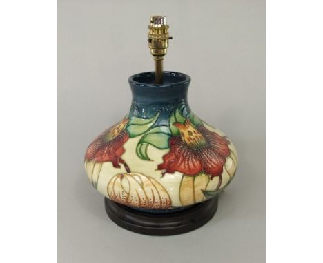 A Moorcroft table lamp base of onion form with painted orange and yellow lily type flower detail on a cream coloured ground, 