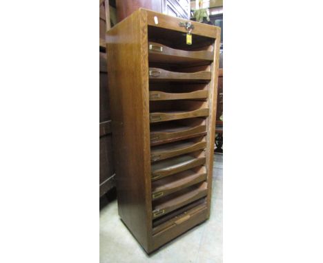 A vintage oak floor standing pedestal filing cabinet, with rise and fall tambour door enclosing nine tray slides