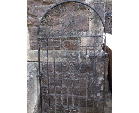 An iron work pedestrian side gate of arched form with scroll work detail and simple thumb latch, 183 cm high x 85 cm wide app