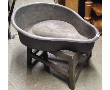 A vintage galvanized saddle shaped basin/planter with central well/channel raised on a wooden stand