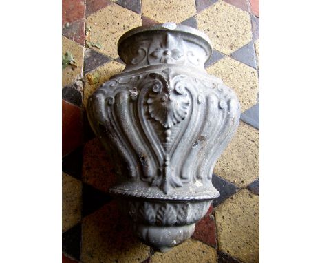 A vintage cast metal wall mounted water vessel with moulded shell, scroll and foliate detail