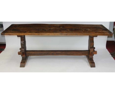 An antique oak refectory table, having  a planked top with cleated ends and some patch repairs, raised on trestle end support