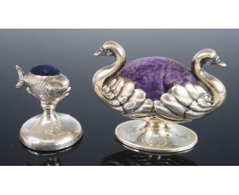 An early 20th century silver novelty pin cushion in the form of two swans, modelled back-to-back with a purple velvet cushion
