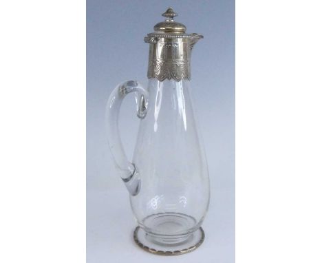 A Victorian silver mounted glass claret jug, having a plain low baluster glass body with applied glass handle, the deep silve