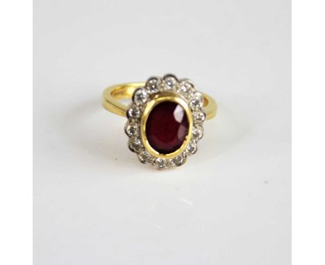 An 18ct yellow and white gold ruby and diamond oval cluster ring, featuring a centre oval facetted ruby within a border of 14