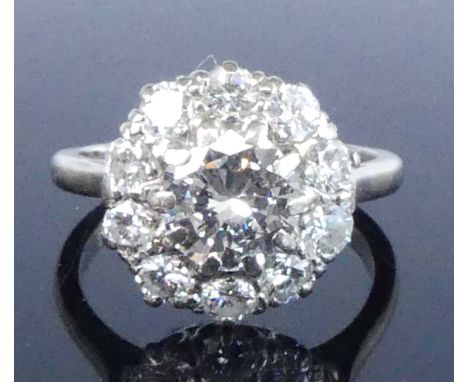 A white metal diamond circular cluster ring, comprising a centre round brilliant cut diamond within a border of ten smaller r