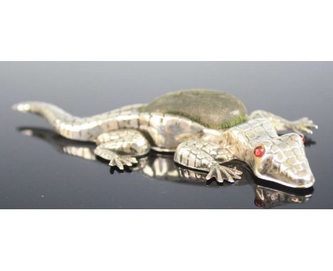 A large Edwardian silver novelty pin cushion in the form of a crocodile, having scale detail to the body and red glass inset 