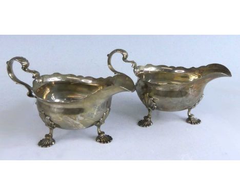 A pair of George II silver sauceboats, each of plain oval form with shaped rims and scrolling acanthus leaf capped handles, e