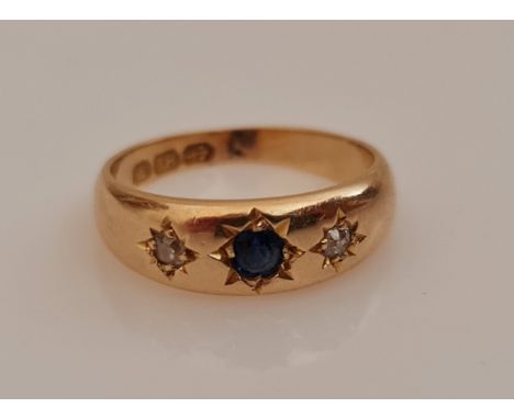 A hallmarked 18ct yellow gold sapphire and diamond three stone ring, star set with a central sapphire flanked to either side 