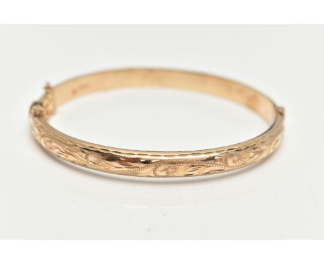 A 9CT GOLD HINGED BANGLE, engraved floral pattern to the front, fitted with an integrated push piece clasp with additional sa
