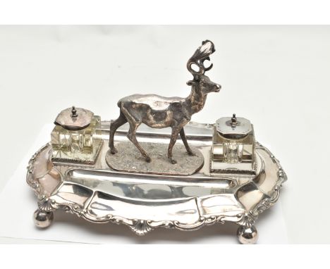 A LATE VICTORIAN SILVER PLATE DESK STAND, featuring a stag to the centre, with two glass ink jars fitted with white metal hin