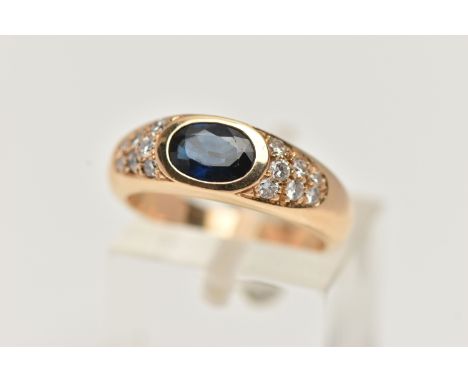 A YELLOW METAL SAPPHIRE AND DIAMOND RING, designed with a central oval cut deep blue sapphire, flanked with round brilliant c