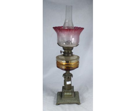A Victorian brass oil lamp with cranberry-tinted and etched shade glass reservoir, 65cm high