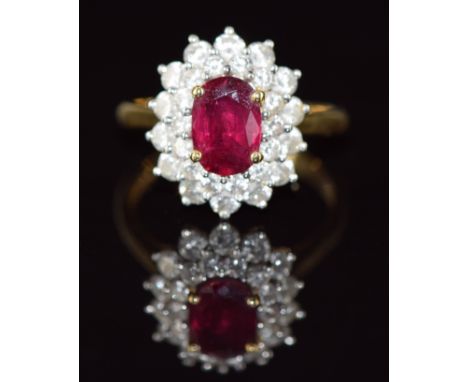 An 18ct gold ring set with an oval cut ruby of approximately 1.1ct surrounded by two rows of diamonds, total diamond weight a