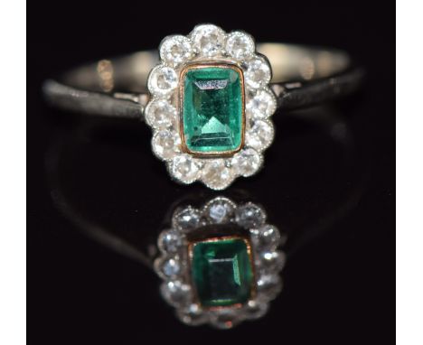 A c1920 18ct gold and platinum ring set with an emerald cut emerald surrounded by diamonds, 1.8g, size O