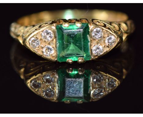 An 18ct gold ring set with an emerald cut emerald of approximately 0.5ct and three diamonds to each shoulder, 4.4g, size P