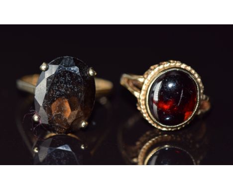 Two 9ct gold rings, one set with a garnet cabochon the other a smoky quartz, 7.6g, size H &amp; R
