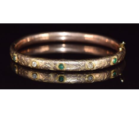 A 9ct gold bangle set with emeralds and diamonds with engraved floral decoration, 14.7g, 6.2 x 5.2cm