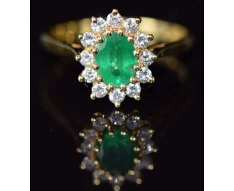 An 18ct gold ring set with an oval cut emerald of approximately 0.7ct and diamonds, 3.2g, size M