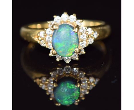 An 18ct gold ring set with a black opal cabochon surrounded by diamonds, 3.8g, size K