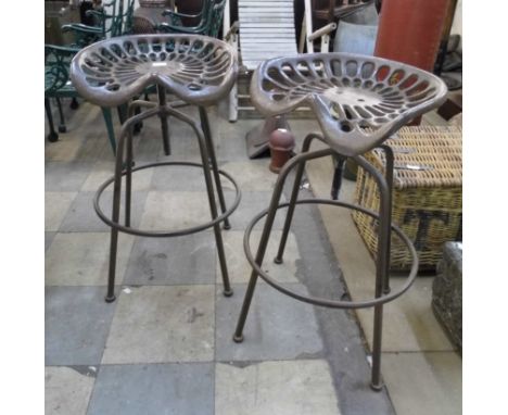 A pair of metal tractor seat style revolving stools 