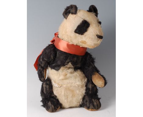 An early 20th century straw filled and mohair childs panda bear, with orange silk collar, heavily worn (possibly Steiff)