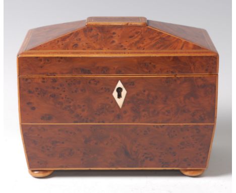 A late George III burr-yew, boxwood strung and rosewood cross banded tea caddy of sarcophagus form, the hinged lid revealing 