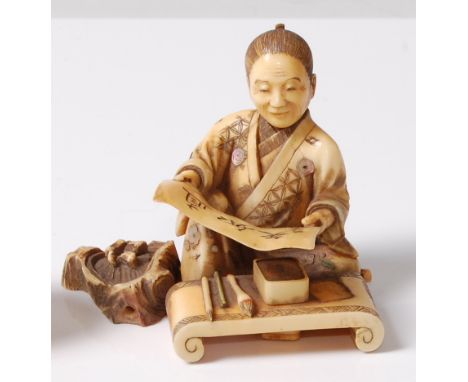 A Japanese Meiji period carved ivory okimono of a calligraphy artist at his desk admiring his work, with shibayama inlays of 