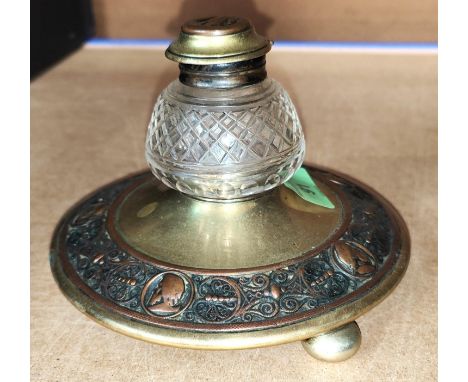 A Victorian brass circular inkwell decorated with relief copper band depicting male head silhouettes; etc.. 