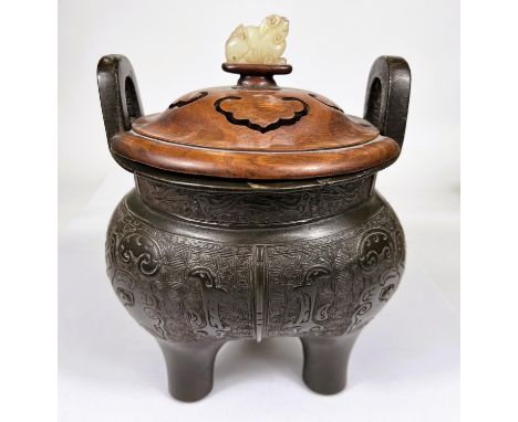 A Chinese bronze censer with 2 large hoops and fitted pierced wooden lid with jade finial, on 3 legs, scrolling decoration of
