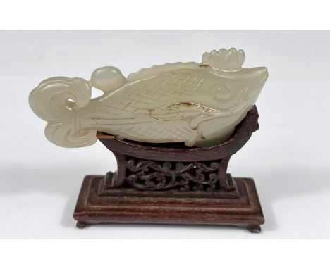 A Chinese jade coloured hardstone carving of a fish on associated stand, length 9cm 