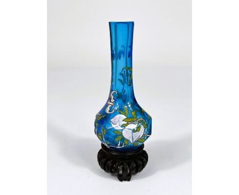 A Chinese light blue glass vase with decoration of fruit and bats on trees with signature to base and a hardwood stand, ht. 1