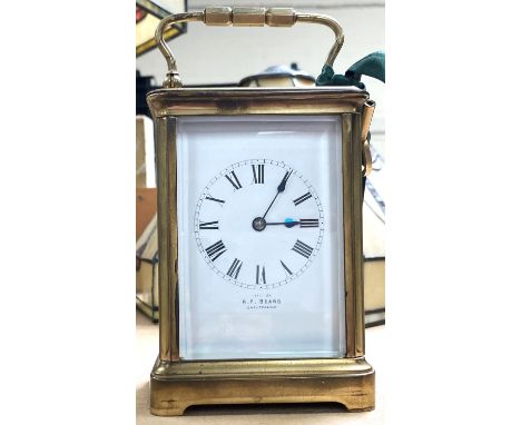 A late 19th/early 20th century brass carriage clock with bevelled glass, white enamel dial by R. F. Beard Cheltenham, strikin