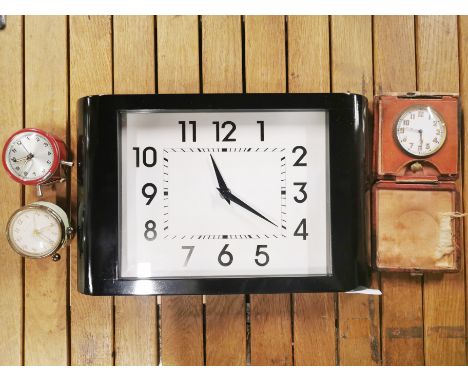 A vintage leather folding travel clock with two small alarm clocks and a battery operated wall clock.