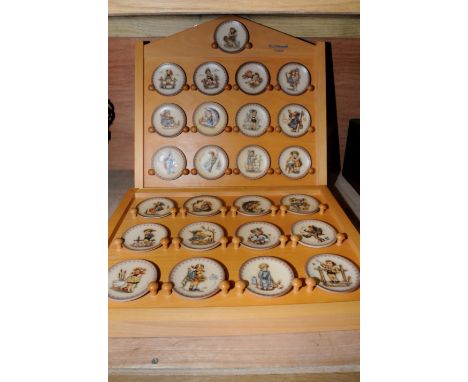 Two wooden display cases with selection of miniature Hummel plates 