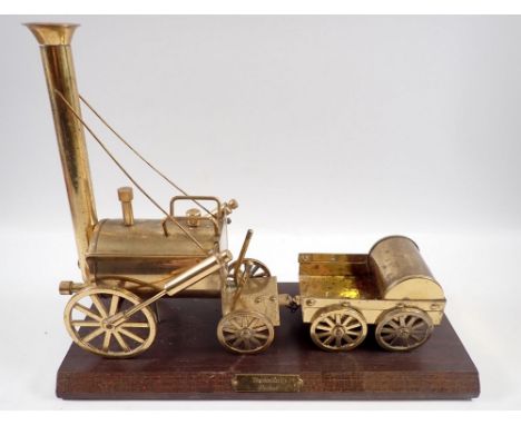 A vintage brass model of Robert Stephenson's Rocket Locomotive on wooden plinth, 32cm long