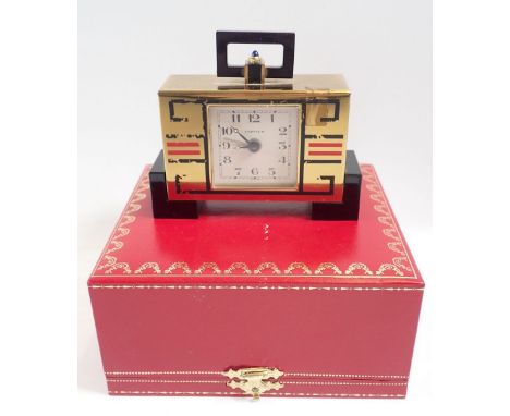 A Cartier Art Deco style brass alarm clock with black and red geometric decoration, 10cm wide with original box