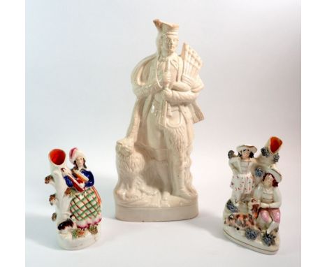 A large Staffordshire figure of a Scottish man with bagpipes and dog, 37cm tall plus two smaller Staffordshire groups