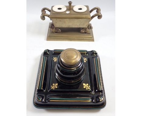 A Victorian black pottery inkwell with brass lid and a brass inkwell on dragon supports, 20cm wide