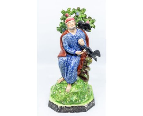 An early 19th Century Staffordshire model of Elijah and the Ravens, circa 1820/40., Elijah seated in blue robe with bocage be